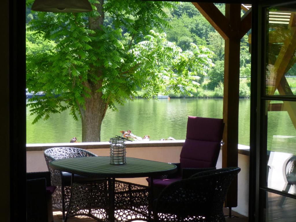 a patio with a table and chairs and a view of a lake at Moselidyll in Traben-Trarbach