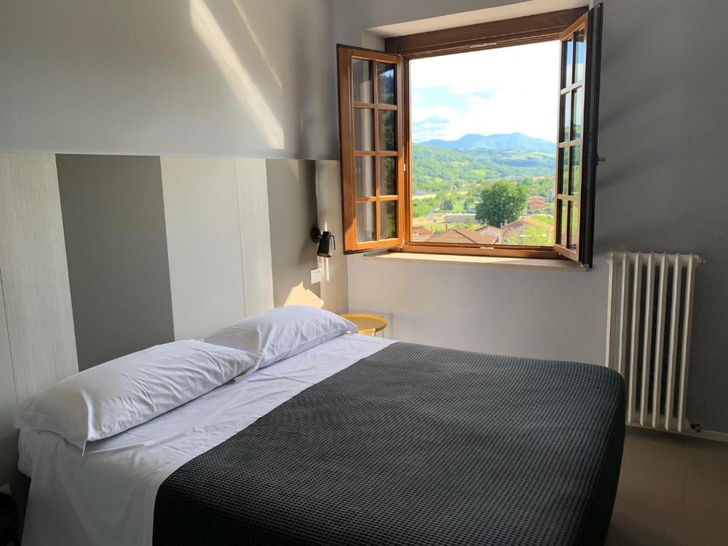 Schlafzimmer mit einem Bett und einem Fenster in der Unterkunft Locanda della Posta in Castelplanio