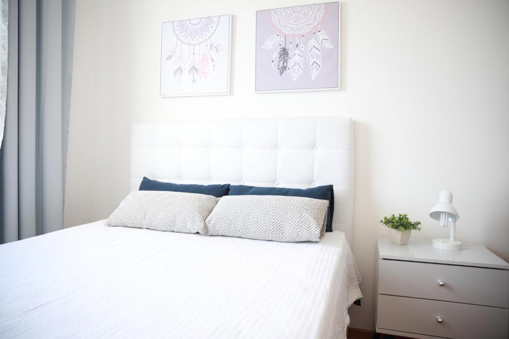 a bedroom with a white bed with a white headboard at Apartamento novo 3 quartos in Diamantina