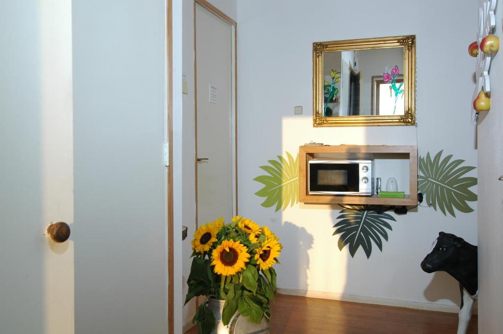 een vaas met zonnebloemen in een kamer met een magnetron bij Bed and Breakfast Tulip Gallery in Amsterdam