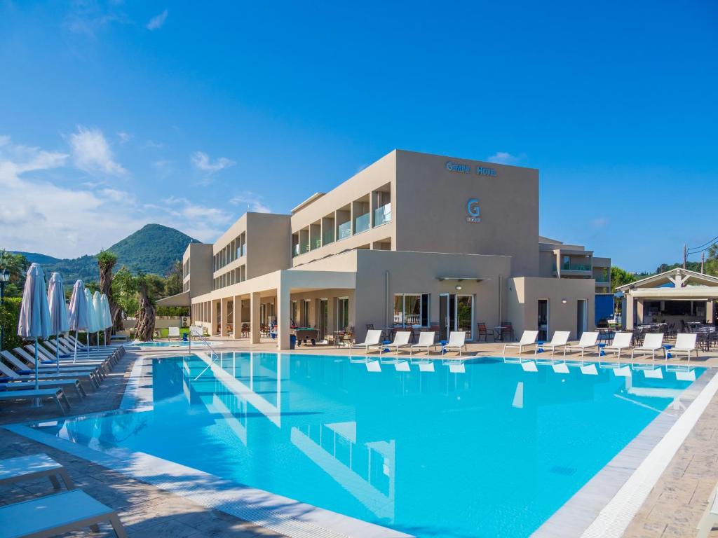 a large pool with chairs and umbrellas in front of a building at CNic Gemini Hotel in Mesongi