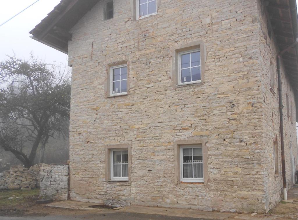 un edificio de piedra con cuatro ventanas en el lateral. en Jurahaus Maisonette Wohnung en Solnhofen