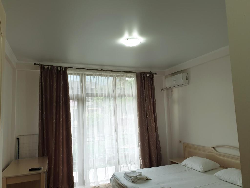 a bedroom with a bed and a large window at Guest House Ontario in Gagra