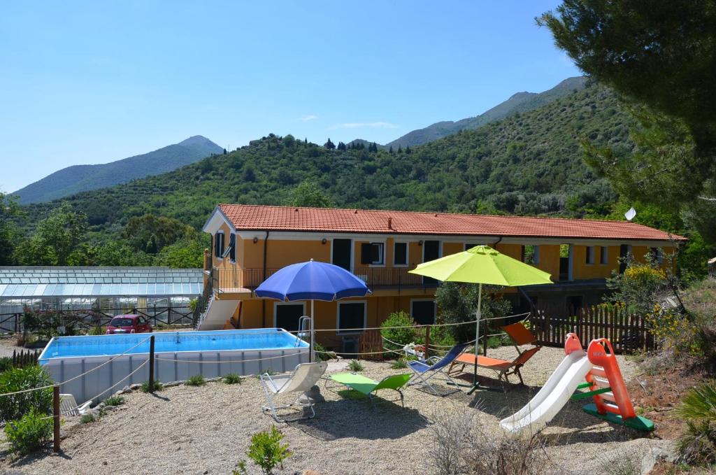 a house with a playground with a pool and umbrellas at Agriturismo Tendapiccola in Ceriale