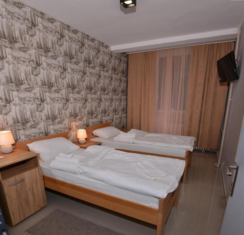 Hotel Timok في Knjazevac.: سريرين في غرفة بها مصباحين وجدار