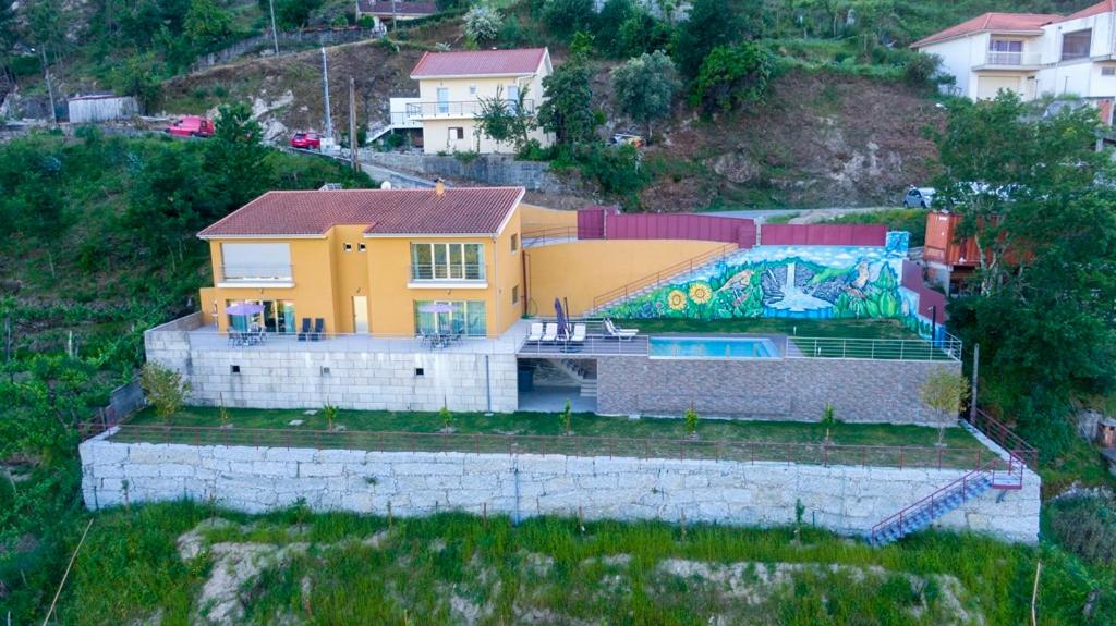 a yellow house with a painting on the side of it at Merck Villa Gerês in Rio Caldo