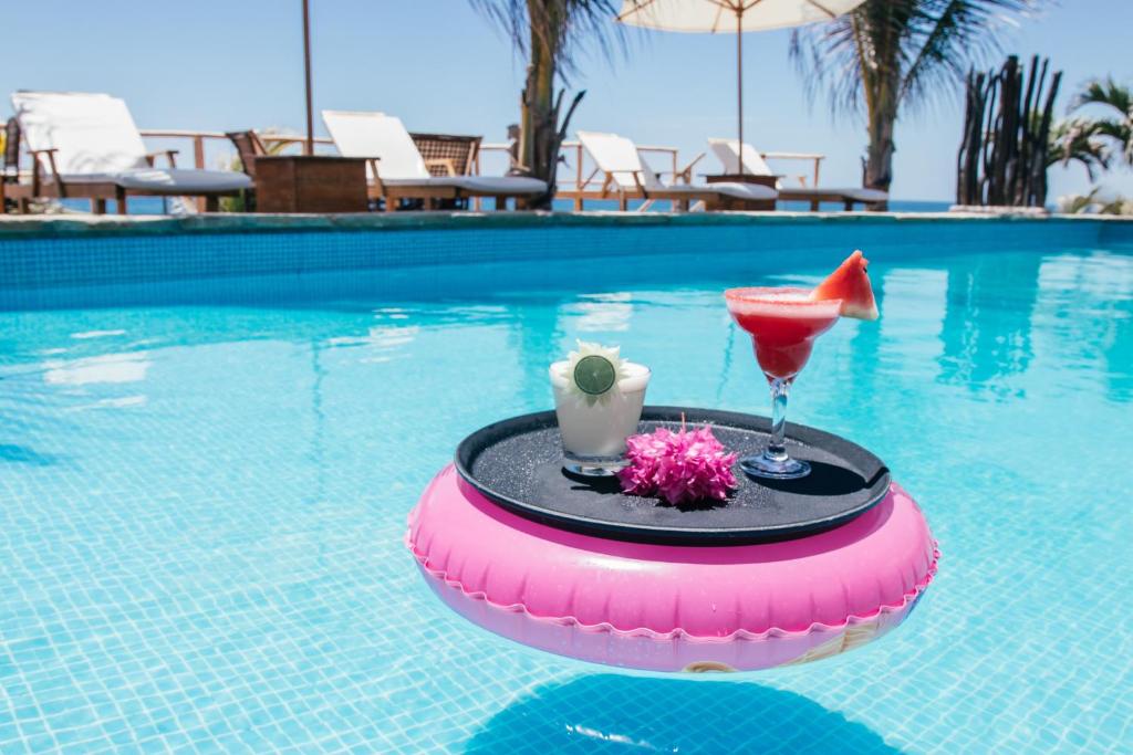 una bebida y un margarita en un flotador en una piscina en Baja Canoas Hotel, en Canoas de Punta Sal