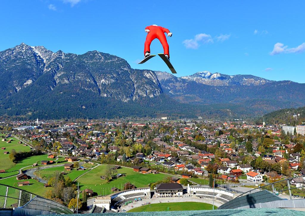 Eine Person in Rot fliegt in der Luft über eine Stadt in der Unterkunft Olympiahaus in Garmisch-Partenkirchen