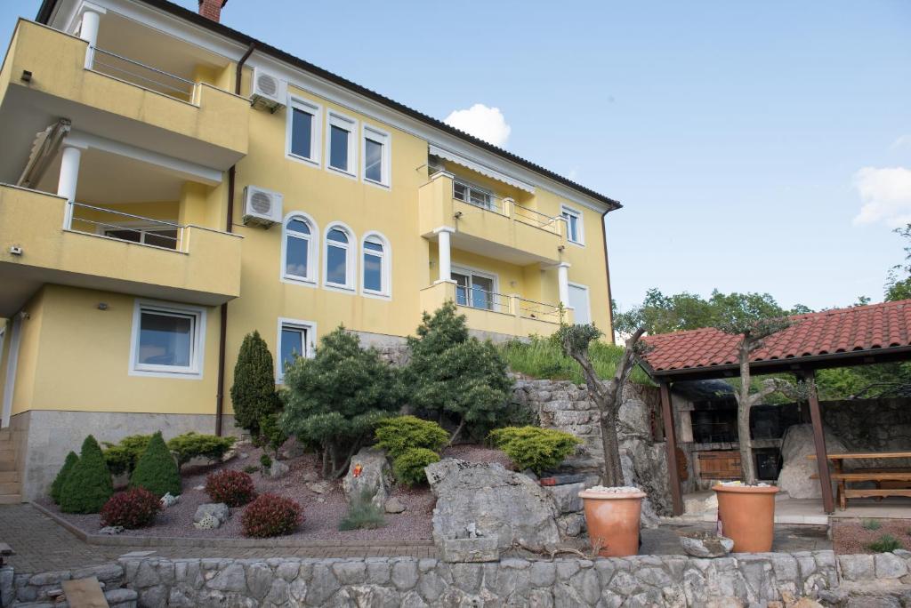 a yellow building with a garden in front of it at Apartmani BILIC in Kastav