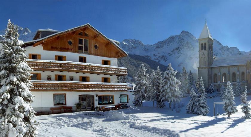 um grande edifício na neve com uma igreja em Hotel Alpenhof em Solda