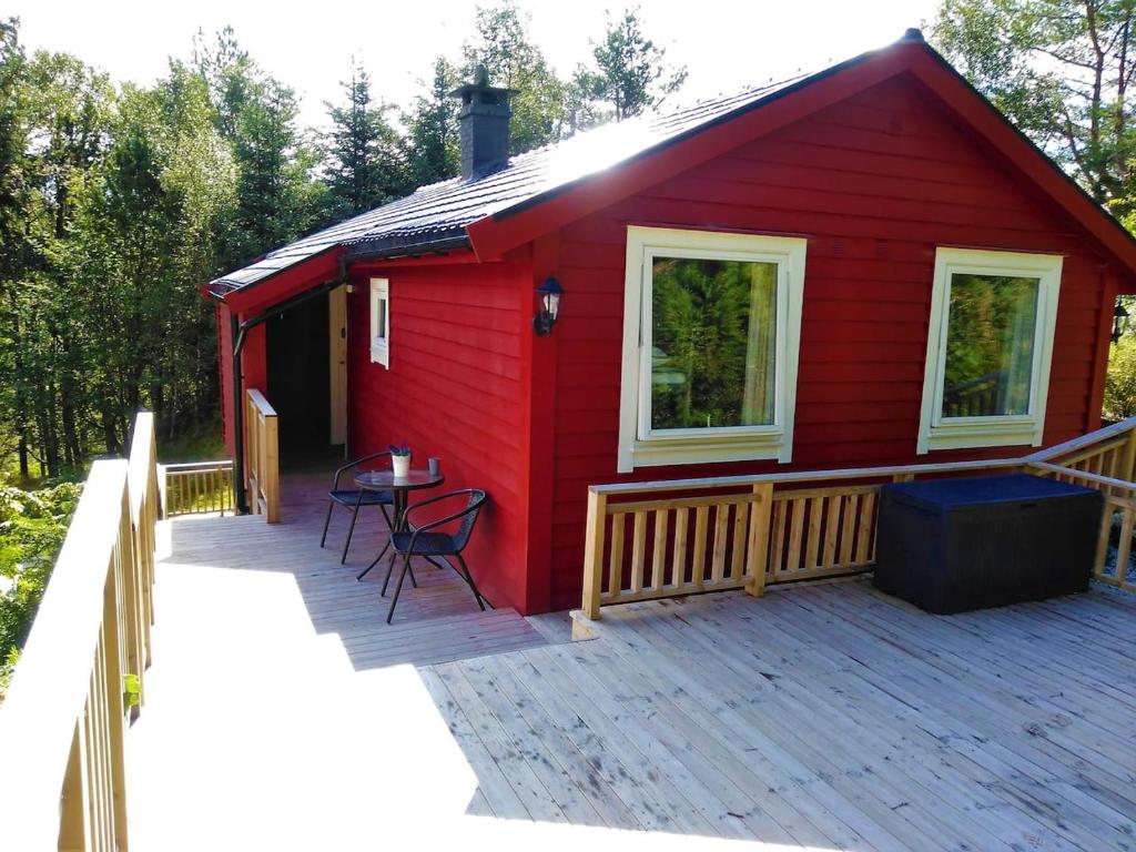 a red house with a deck and a table at Fjellheim in Herlø