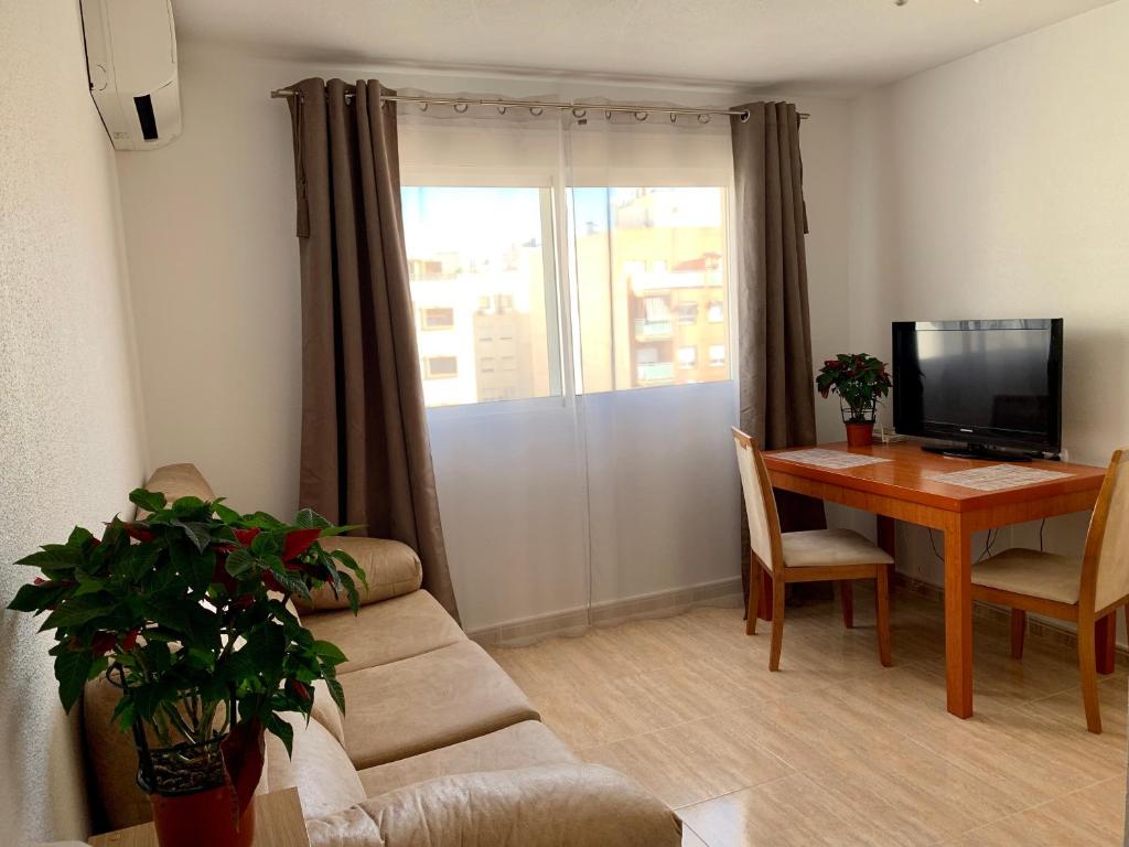 een woonkamer met een bank en een tafel met een televisie bij Apartment in Torrevieja