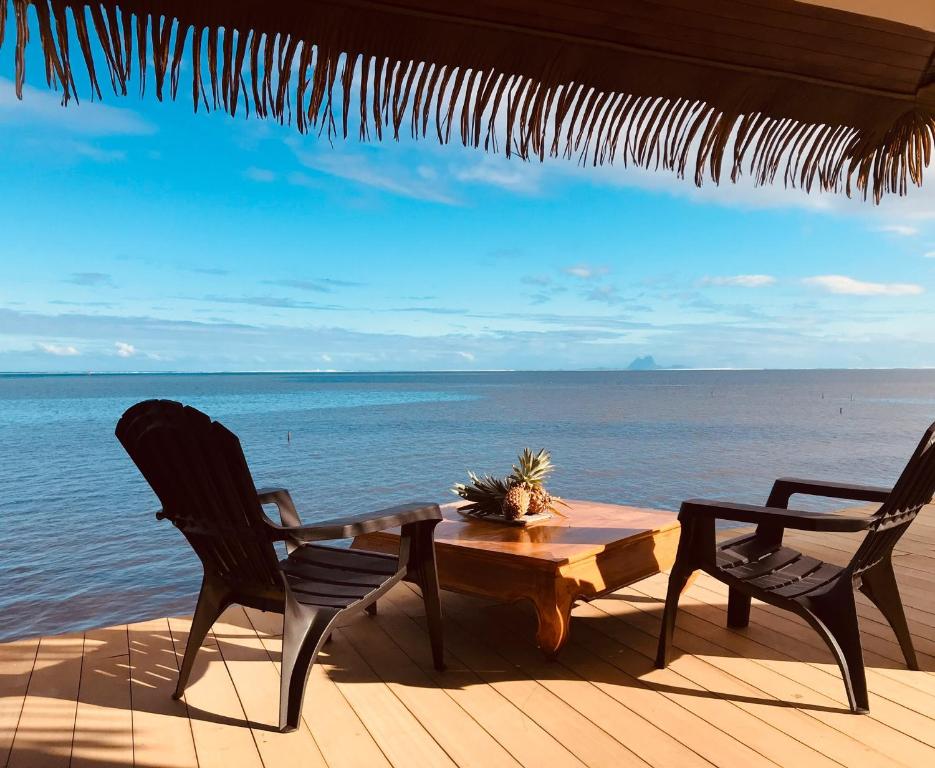 a table and chairs on a deck with the ocean at Ocean Breeze Bungalow in Tevaitoa