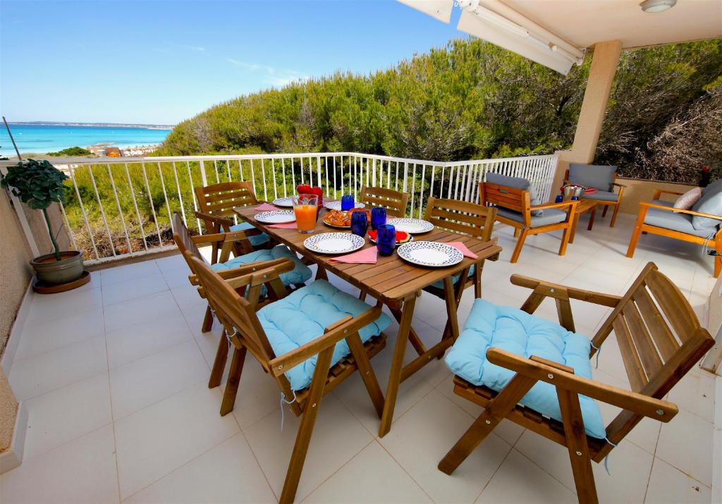 een houten tafel en stoelen op een balkon met uitzicht op de oceaan bij Apartments Es Trenc in Ses Covetes