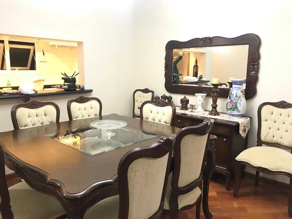 a dining room with a table and chairs and a mirror at Chateau du Loire Apartamento in Campos do Jordão