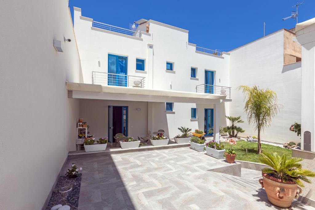 a white house with a courtyard with potted plants at Affittacamere Sirius in San Vito lo Capo