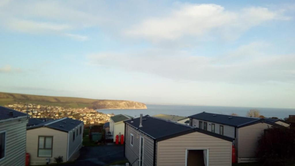 a row of houses with the ocean in the background at Swanage Bay View caravan in Swanage