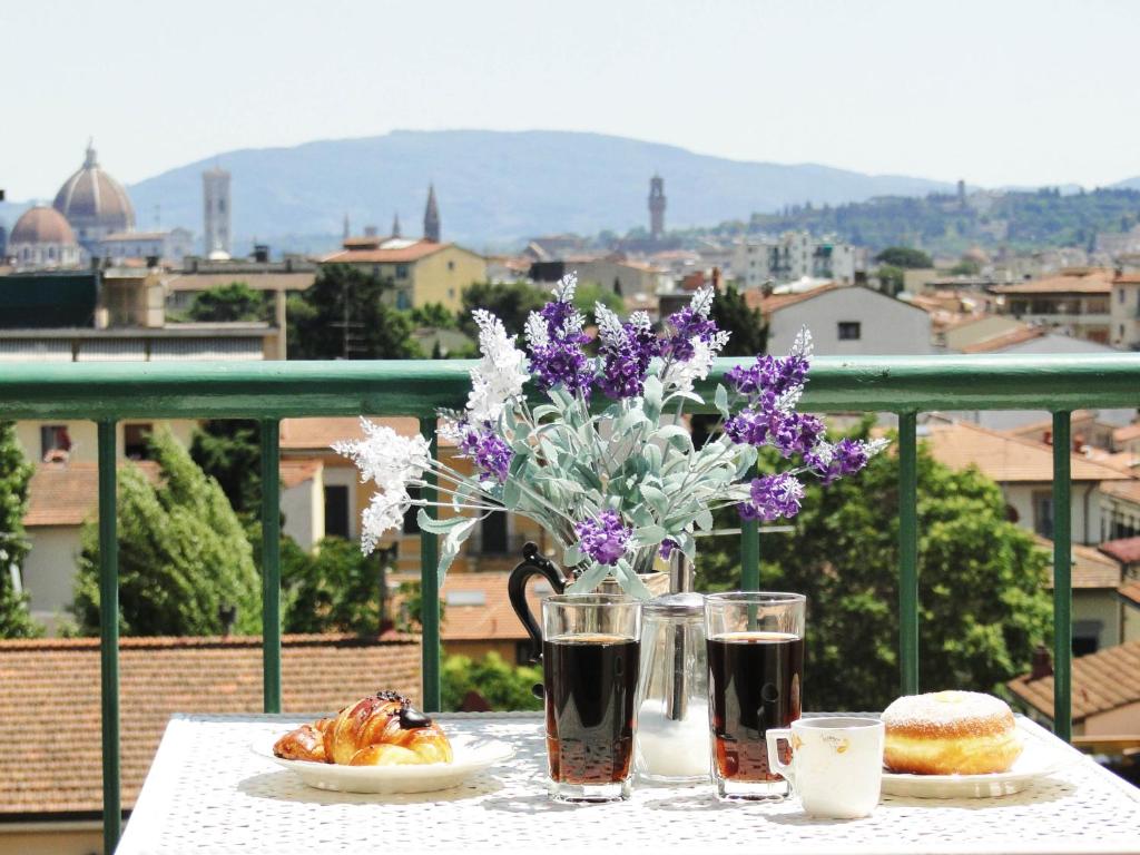 una mesa con dos bebidas y un jarrón con flores púrpuras en Casa Dami en Florencia