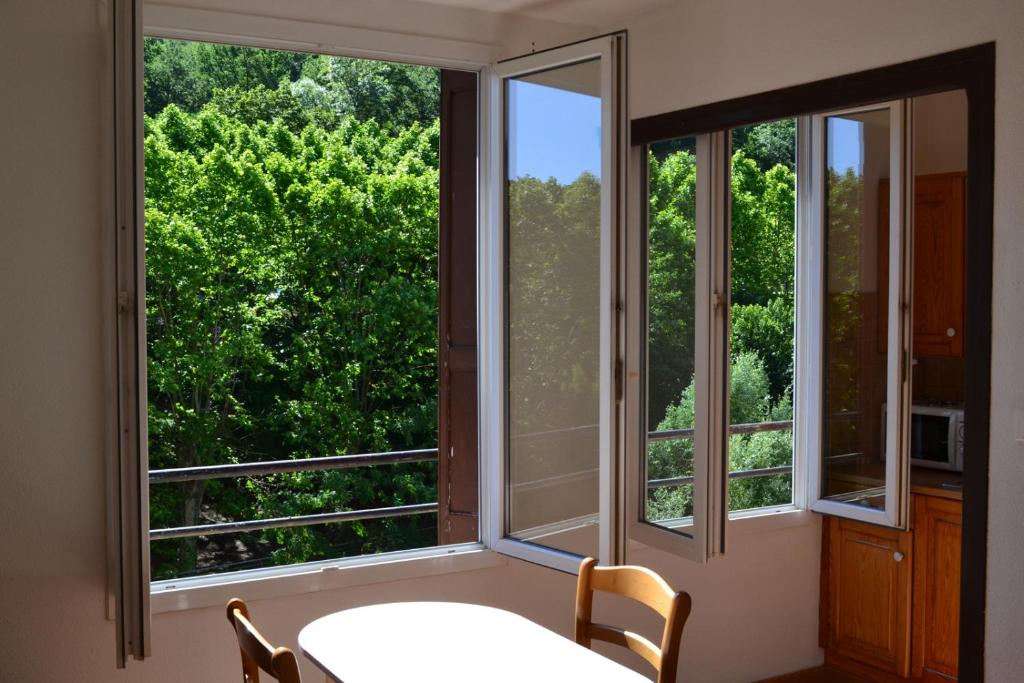 um quarto com duas janelas com uma mesa e cadeiras em Studio à 100 mètres des thermes vue sur montagne. em Amélie-les-Bains-Palalda