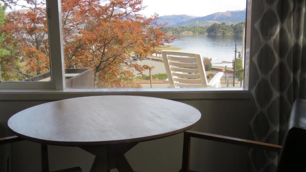 a table in front of a window with a view of a lake at Apart Costanera in Villa Pehuenia