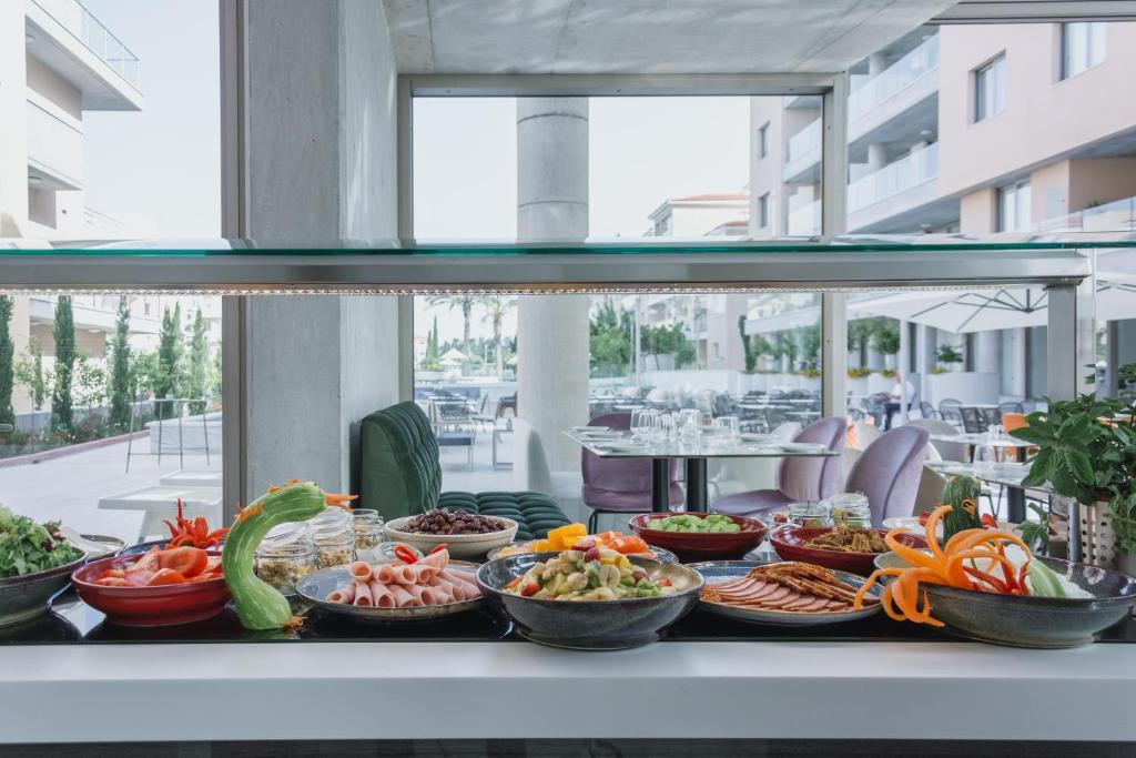 a buffet line with bowls of food on a table at Elysia Park in Paphos