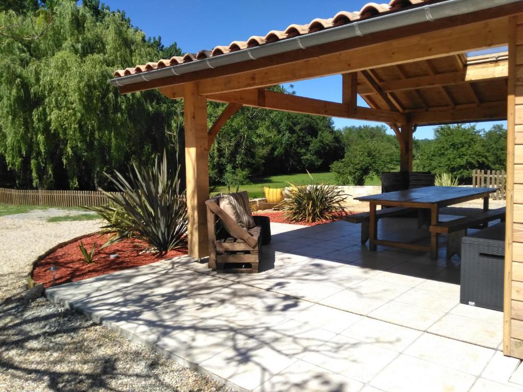 eine Terrasse mit einer hölzernen Pergola und einem Tisch in der Unterkunft Les chambres d'Ausilia in Sablons