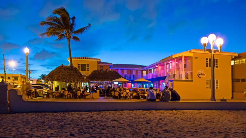 um grupo de pessoas de pé em uma praia à noite em Riptide Oceanfront Hotel em Hollywood