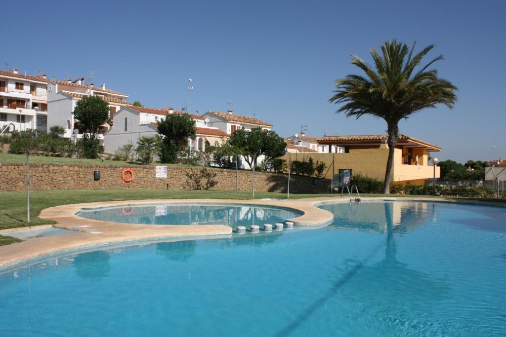 a large swimming pool with a palm tree and buildings at Adosado Peñisol Inmomart in Peniscola