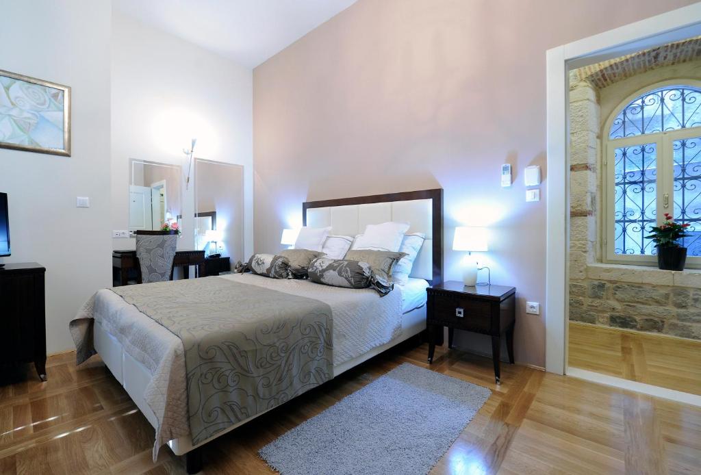 een witte slaapkamer met een bed en een raam bij Palace Augubio in Split