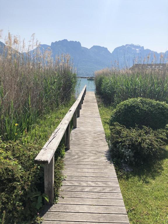une promenade en bois menant à une masse d'eau dans l'établissement Angel Services - LA MAISON DE LA PLAGE, à Sévrier
