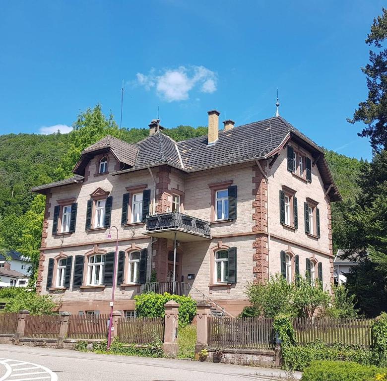 une vieille maison en briques avec une clôture dans une rue dans l'établissement Forsthaus Merzalben Hostel, à Merzalben