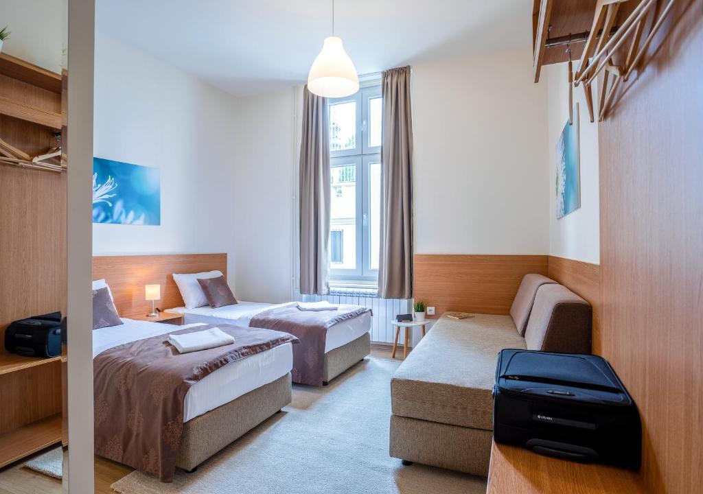 una camera d'albergo con due letti e un divano di Booking En Suite a Belgrado