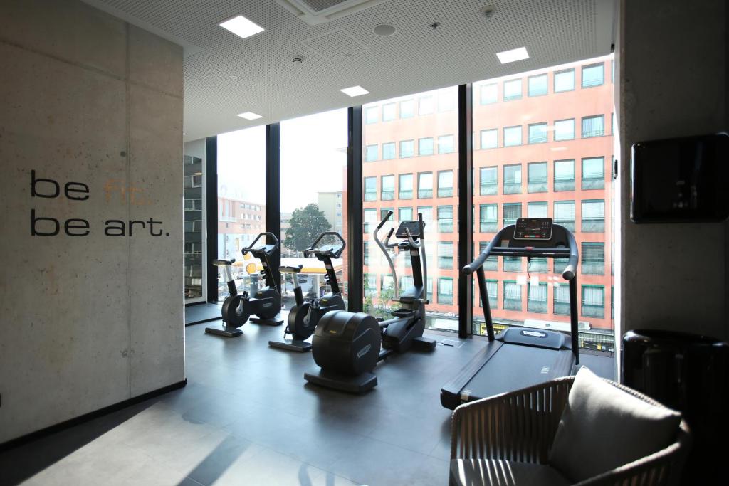 un gimnasio con equipo cardiovascular en una habitación con ventanas en arte Hotel Salzburg, en Salzburgo