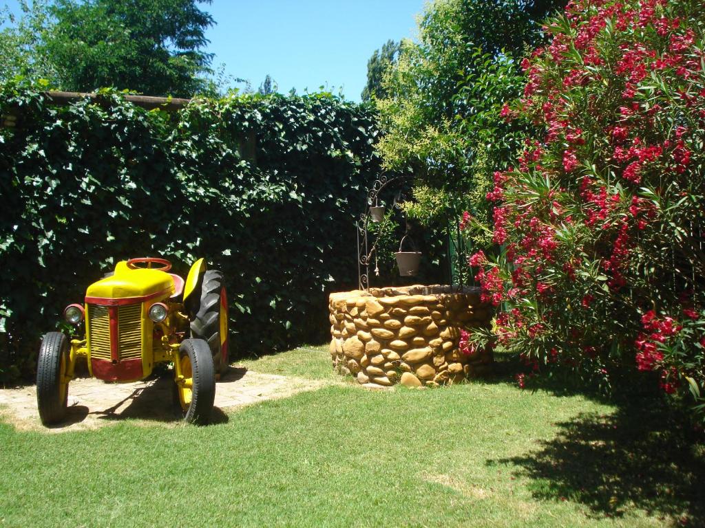 a toy tractor sitting in the grass next to a hedge at Akimekedo in Mendoza
