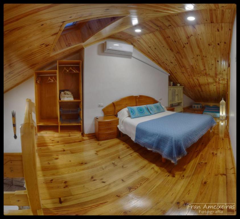 a bedroom with a bed and a wooden floor at A Casa das Burgas in Cuntis