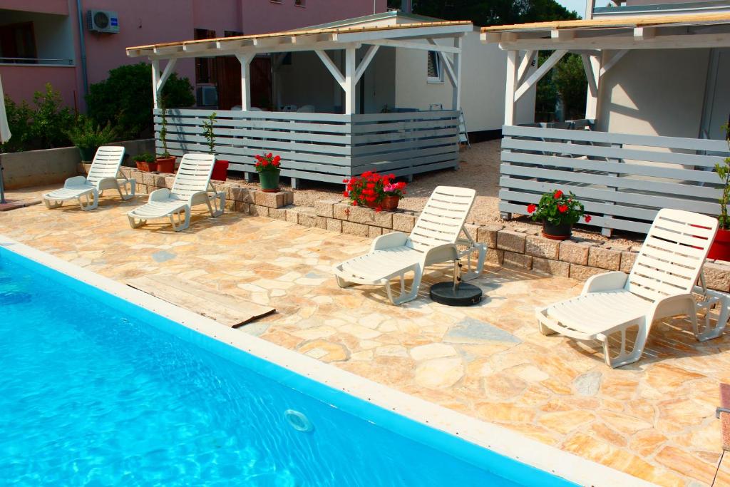 a group of chairs sitting next to a swimming pool at BUNGALOW VICE with pool in Pakoštane