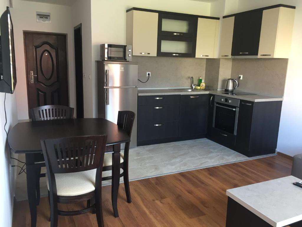 a kitchen with a black table and chairs and a kitchen with a stove at Apartments Dione in Pomorie