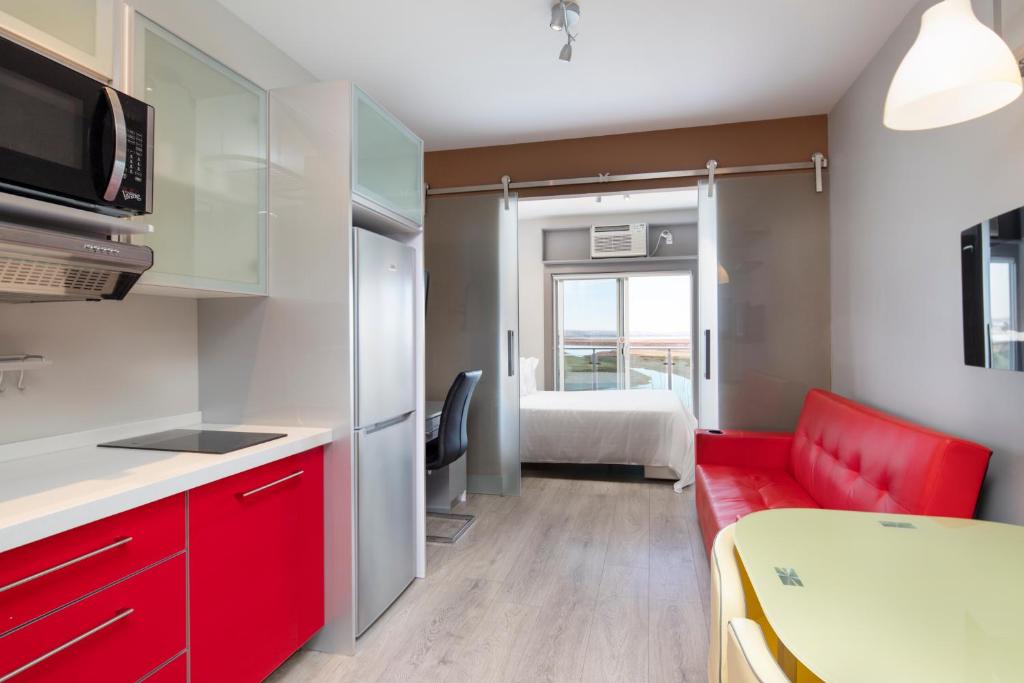 a small kitchen with red cabinets and a red couch at Micro Boutique Living Wolfville in Wolfville