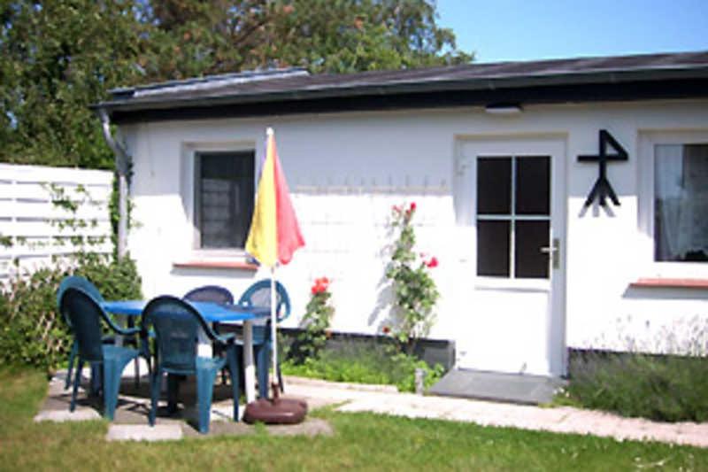 a table and chairs in front of a house at Ferienhaus in Plogshagenauf Hidden in Neuendorf