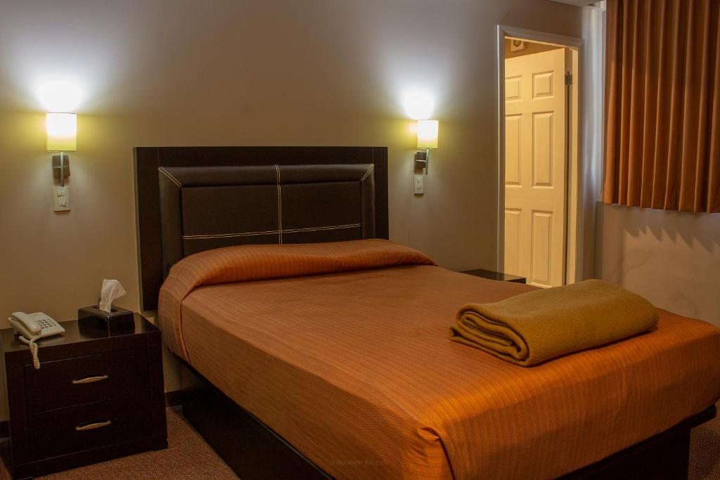 - une chambre avec un grand lit et une couverture orange dans l'établissement BONITTO INN® Tampico Lomas, à Tampico