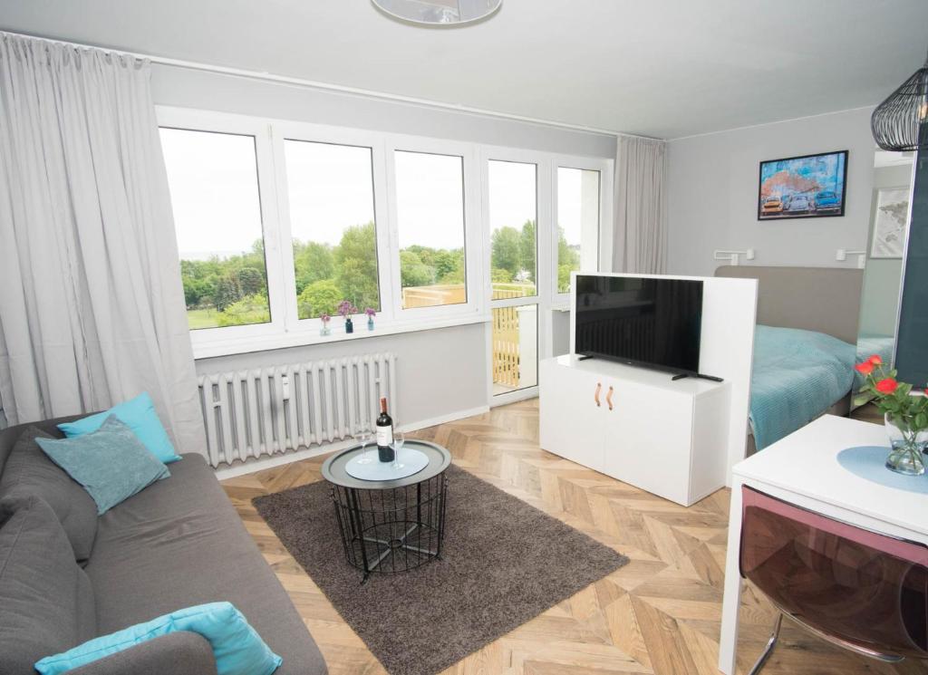 een woonkamer met een bank en een flatscreen-tv bij Apartament Skwer 13 in Gdynia