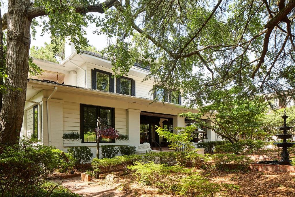 a white house with black windows and a tree at Eden Brae: Historic Southern Gothic Mansion in Birmingham