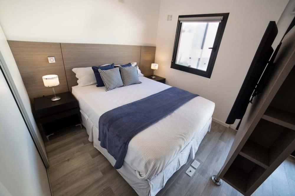 1 dormitorio con 1 cama grande con almohadas azules y blancas en Aventura 109 en Buenos Aires