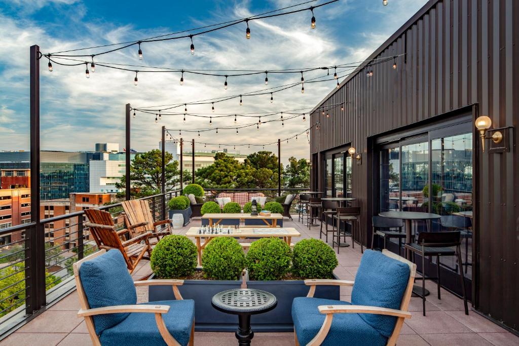 eine Terrasse mit Stühlen und Tischen auf dem Balkon in der Unterkunft Graduate Charlottesville in Charlottesville