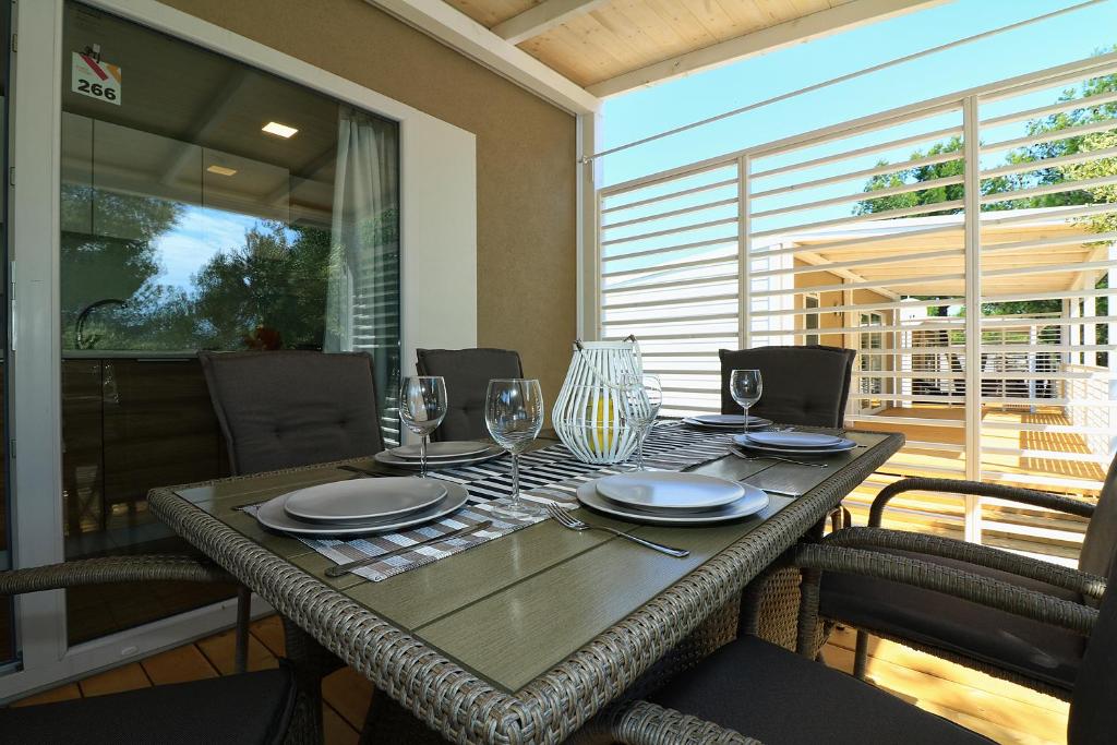 a table with wine glasses and plates on a patio at MOBIL HOMES MALUFI 266 in Jezera