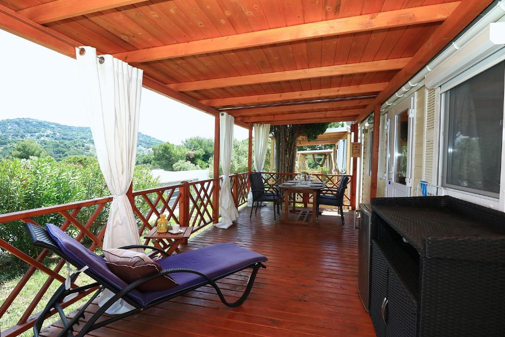 a porch with chairs and a television and a table at MALUFI 193 in Jezera