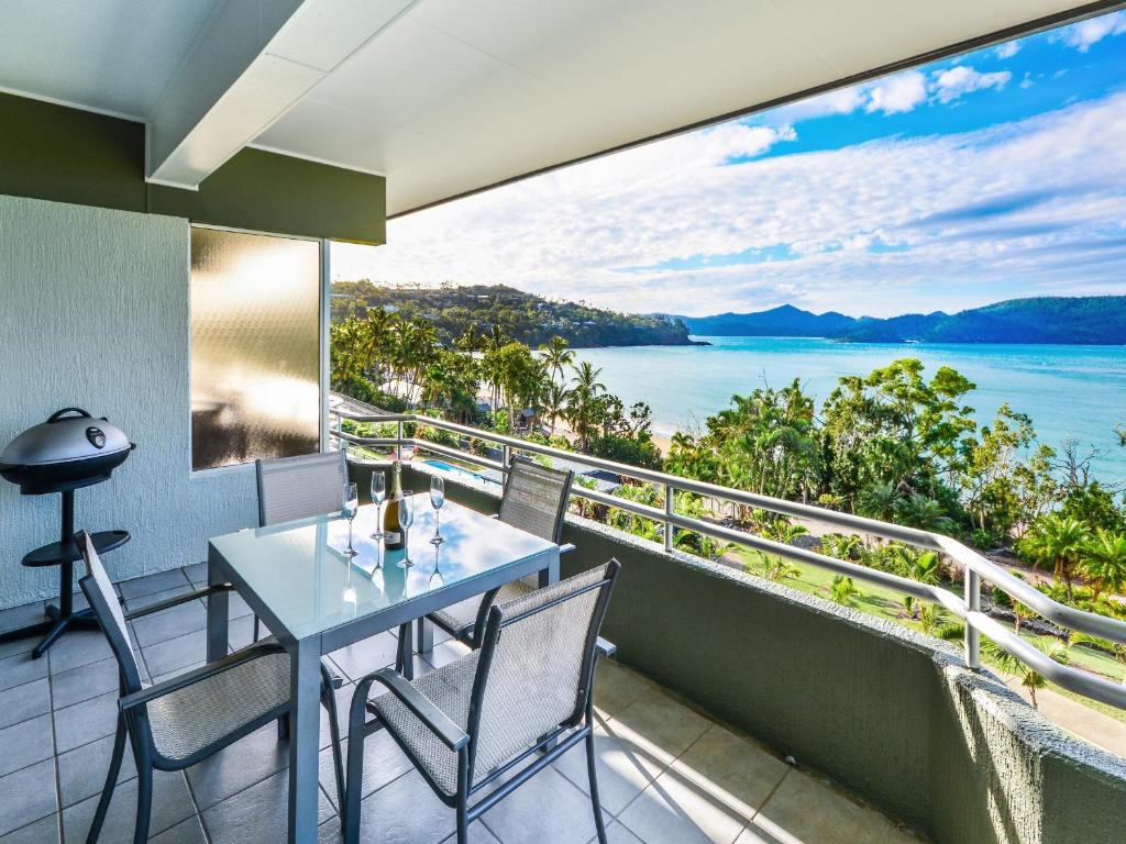 Un balcón con mesa y sillas y vista al agua. en Hibiscus Apartments on Hamilton Island by HIHA, en Hamilton Island