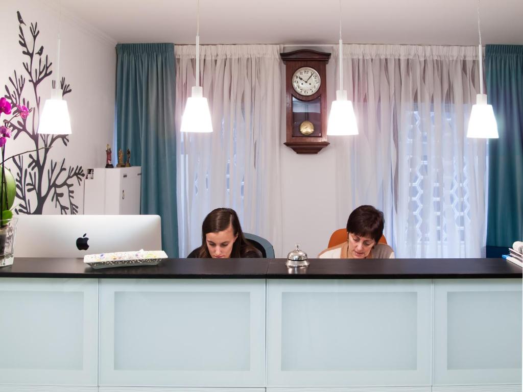 dos mujeres sentadas en un escritorio frente a un espejo en Hostal La Provinciana, en A Coruña
