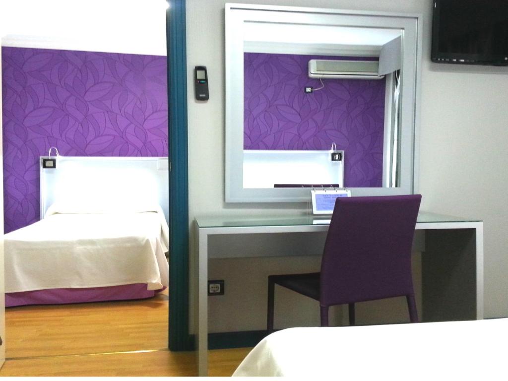 a bedroom with a desk and a mirror and a bed at Hotel Molinos in Granada