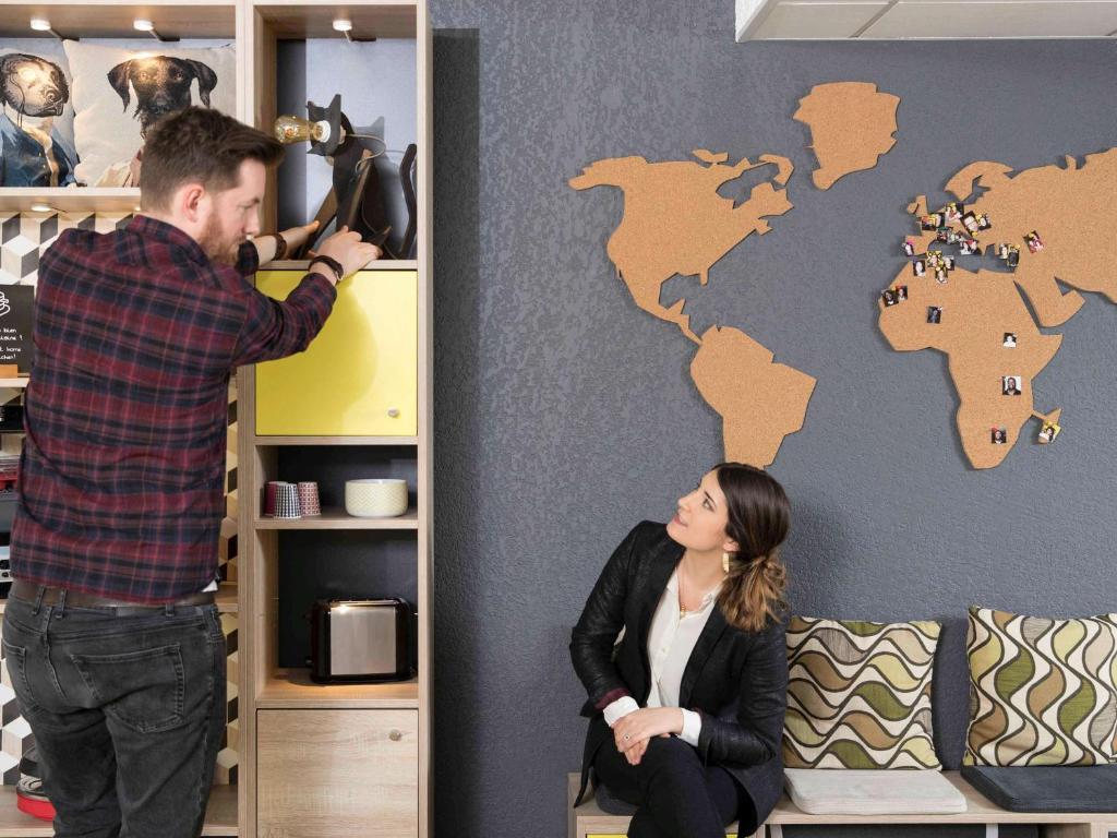 un hombre pintando una pared con un mapa mundial. en Aparthotel Adagio Access Strasbourg Petite France en Estrasburgo